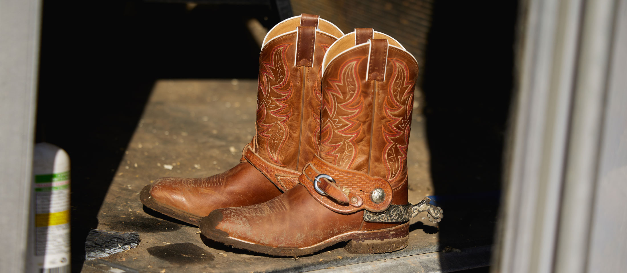 A close up photo of cowboy boots placed in a barn.